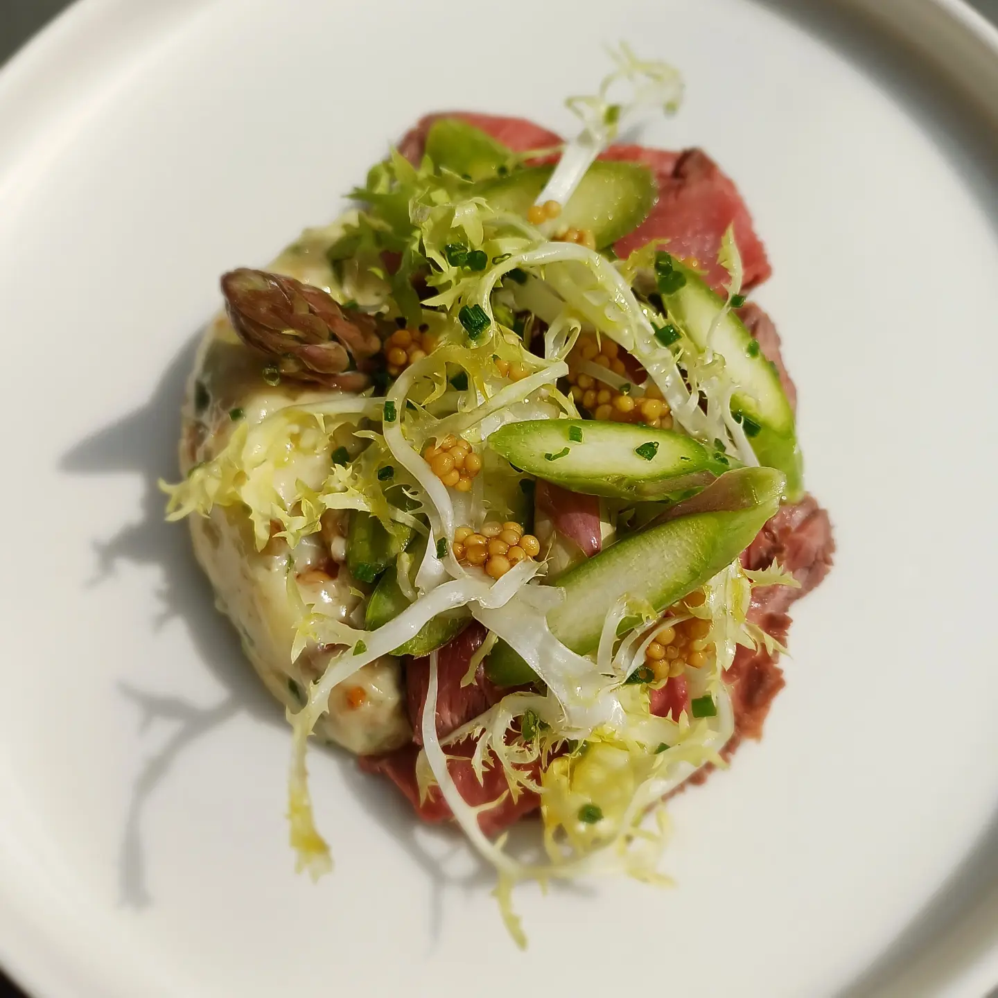 Tyndskåret dansk øko-okse med aspargessalat, syltet sennep og frisée